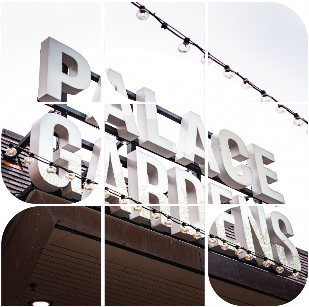 Close-up view of the Palace Gardens entrance sign with illuminated letters and string lights above.